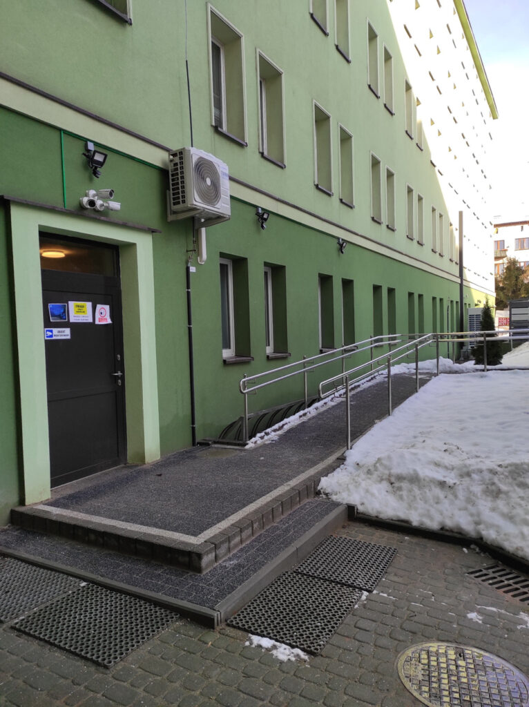 Zdjęcie przedstawia drugie wejście do budynku biurowego (poziom -1), w którym mieści się Regionalny Ośrodek Polityki Społecznej w Rzeszowie od strony samochodowego parkingu wewnętrznego Ośrodka.