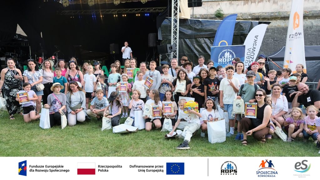 Duża grupa rodzin z dziećmi pozujących przed sceną