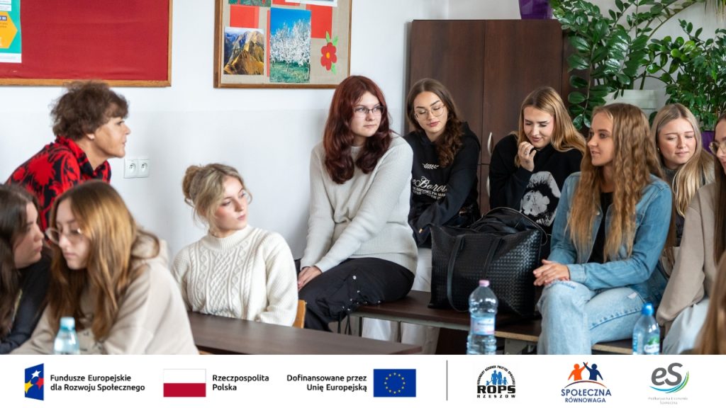 Zdjęcie grupy nastolatków siedzących na biurkach i słuchających prelegenta