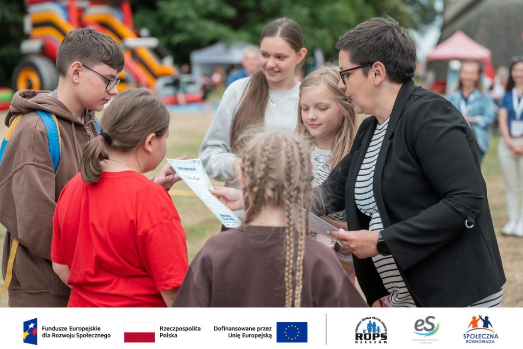 Kobieta rozdająca dyplomy dzeiciom