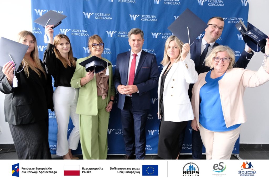 Grupa ludzi pozująca do zdjęcia z czapkami studenckimi