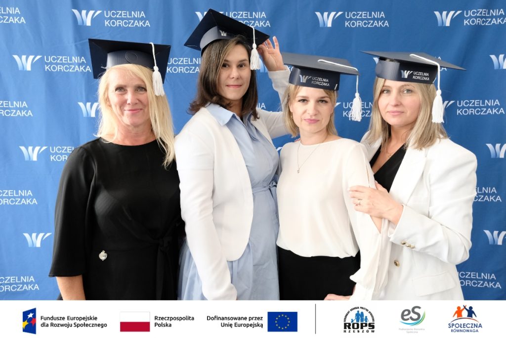 Grupa ludzi pozująca do zdjęcia z czapkami studenckimi
